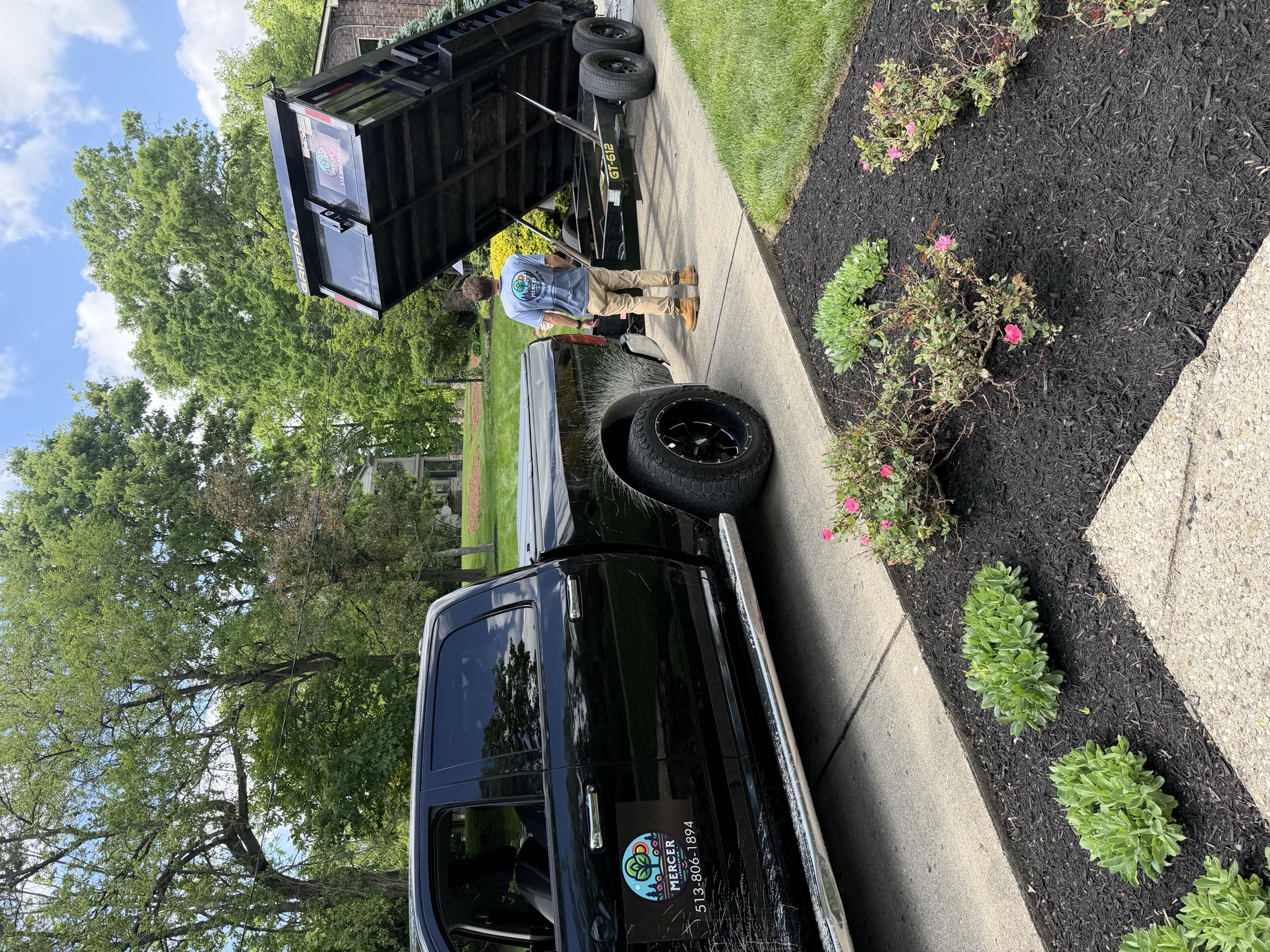 Mercer Landscaping truck and crew member beside a freshly mulched residential landscape bed