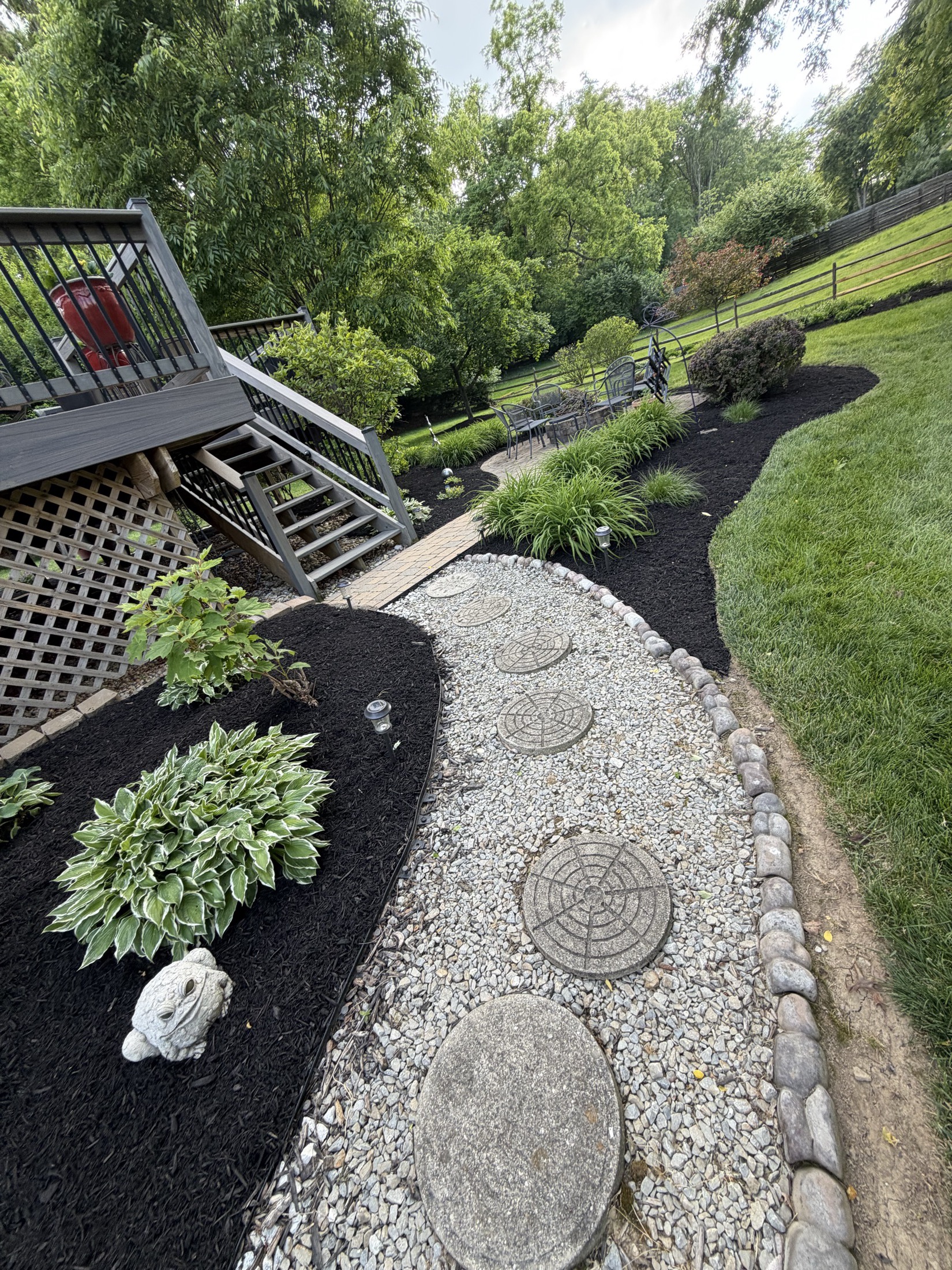 River rock pathway through fresh black mulch and plants